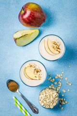 Healthy breakfast apple oat smoothie in glasses on light blue background. Top view, copy space.