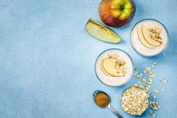 Peanut butter apple oatmeal smoothie in glasses on light blue background.Top view, copy space.
