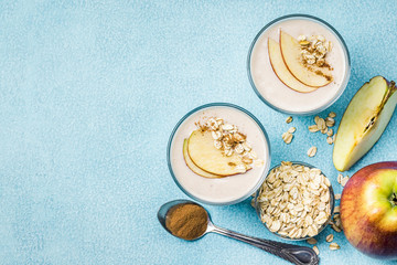 Creamy apple pie oatmeal smoothie in glasses on light blue background. Top view, copy space.