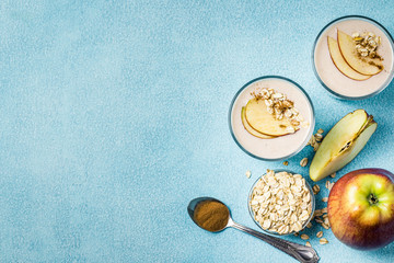 Apple cinnamon oatmeal smoothie in glasses on light blue background. Top view, copy space.