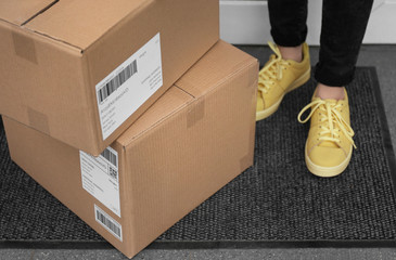 Woman standing near delivered parcels on doormat, closeup
