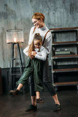 Naklejka premium happy young mother and daughter playing in loft apartments
