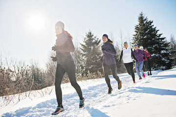 Group of friends enjoying jogging in the snow in winter