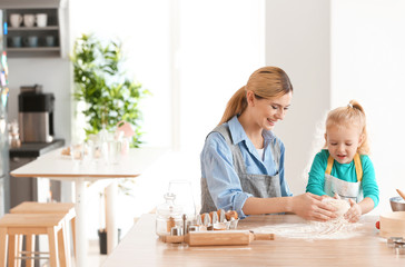 Mother and daughter with dough at table indoors