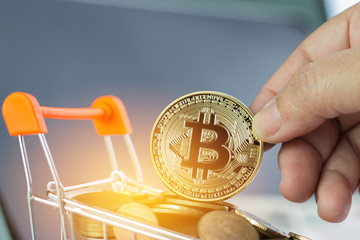 Hands holding Bitcoin Digital Virtual money on Coins shopping cart. Concept of e-commerce, use Bitcoin payment transaction of buying, selling goods and services online Exchange Virtual payment.