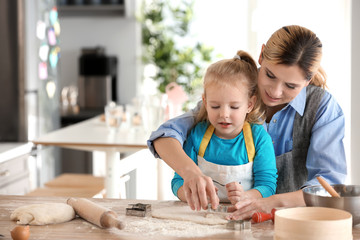 Mother and daughter with dough at table indoors