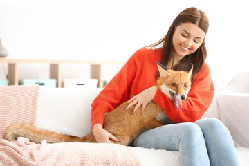 Fototapeta na wymiar Young woman with pet fox indoors