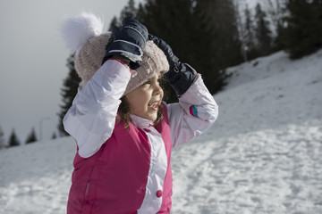 Fototapeta na wymiar A cute joyful little girl smiling. Snowy winter landscape. Copy negative space. Selective focus