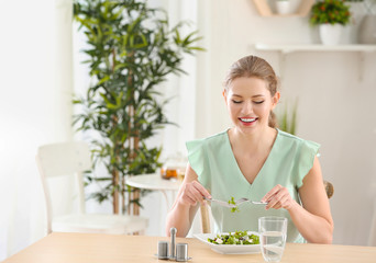 Obraz na płótnie Canvas Young beautiful woman eating fresh salad at home