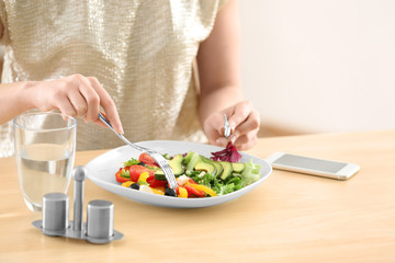 Fototapeta na wymiar Young woman eating fresh salad at table