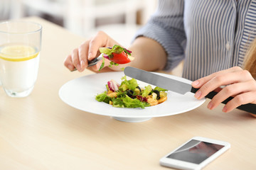 Obraz na płótnie Canvas Young woman eating fresh salad at table