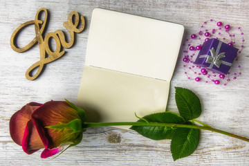Valentine's composition with a red rose on a notebook, a gift and the words 
