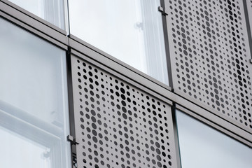 Modern building facade with perforated metal shading and glass