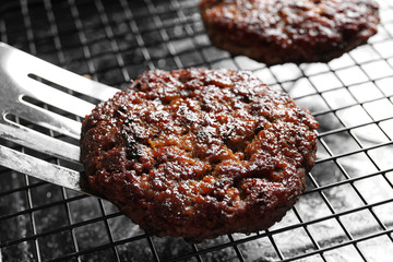 Spatula and burger patty on grill, closeup