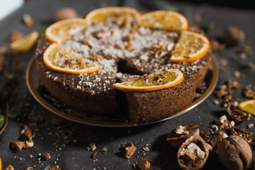 Beautiful and tasty chocolate cake with orange and nut on a dark background