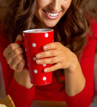 Happy young woman in christmas red dress having cup of hot bever