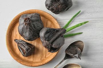 Plate with black garlic (Allium sativum) on wooden table