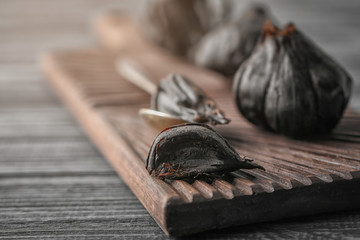 Black garlic (Allium sativum) on wooden board
