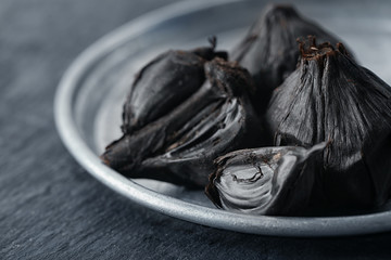 Plate with black garlic (Allium sativum) on table © Africa Studio