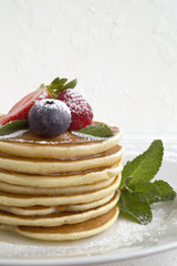 American pancakes with berries on a light background.