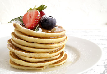 American pancakes with berries on a light background.