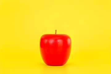 Artificial wooden apple on yellow background.