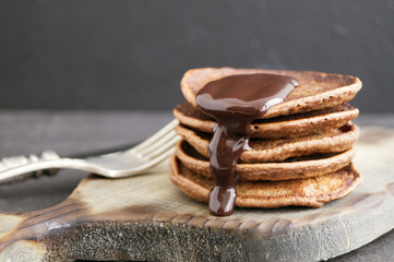 Chocolate pancakes with chocolate sauce on a dark background.