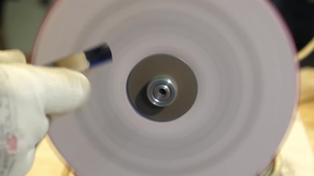 Sharpening a chisel on grinding machine with fly sparks