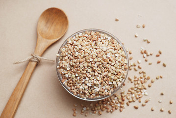 Top view of Raw Green Buckwheat and Brown roasted buckwheat in Glass Bowl on Ivory Background. Healthy food and diet concept. Flat lay. Wooden Spoon. Copy space.