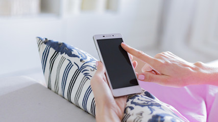 Woman at home relaxing reading on the smartphone 