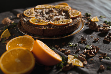 Beautiful and tasty chocolate cake with orange and nut on a dark background