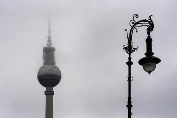 Old and new Berlin TV tower (Fernsehturm) and a street lamp in deep fog - landmark of Germany...