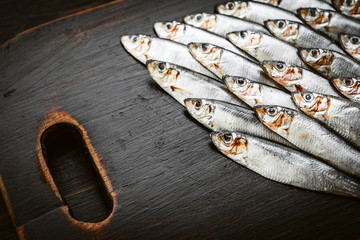 fresh raw fish anchovy and sprat on a wooden surface