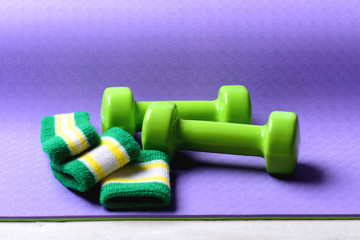 Dumbbells made of green plastic on purple background.