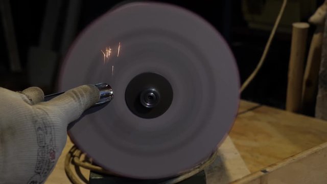 Sharpening a chisel on grinding machine with fly sparks