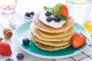 Stack of pancakes on the plate. Morning breakfast with berries on the table. Close up