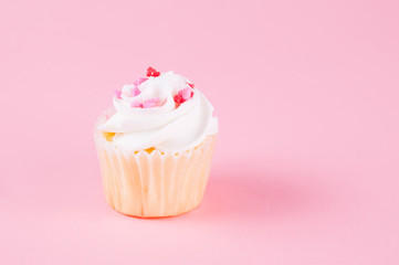 cupcake with heart confetti on a pink background for valentine's day
