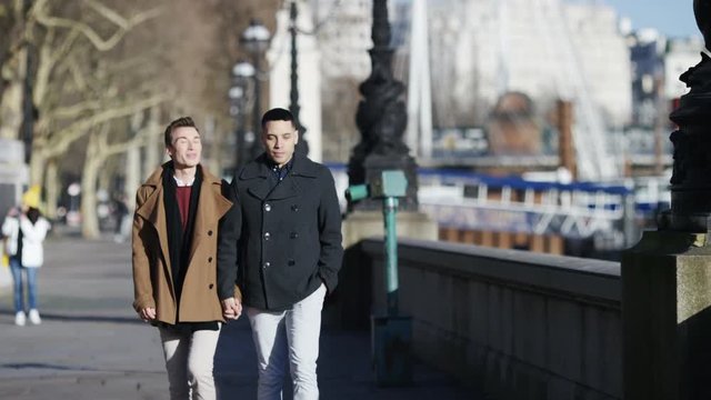 Happy diverse same sex couple walking hand in hand and having fun