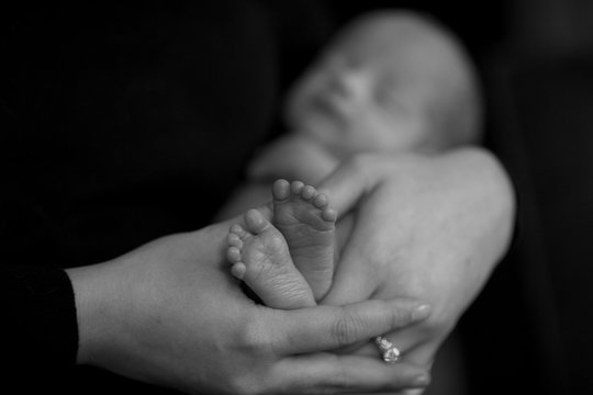 Loving mother holding baby feet in black and white