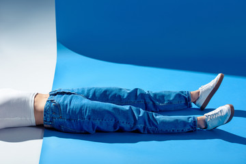 cropped image of stylish girl lying on white and blue floor in jeans