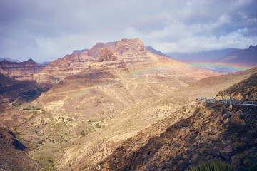 Rainbow over road into mountain landscape of Gran Canaria island, Spain / Valley of 