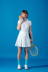 tennis player standing with orange and tennis racket on blue
