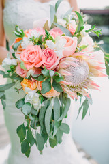 Bride holds a bouquet with proteus and roses. Wedding day