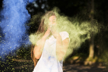 Cheerful tanned asian girl dressed in white shirt,  playing with Holi powder