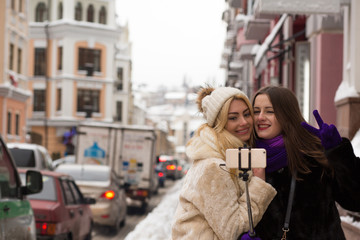 Two positive girls friends taking a self portrait at the city using mobile phone
