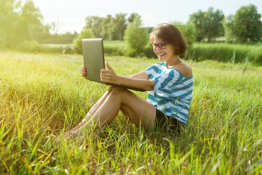 Smiling Woman Rests In Nature And Talks On Video Call