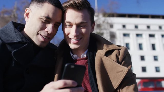 Happy young same sex couple looking through a phone take a selfie