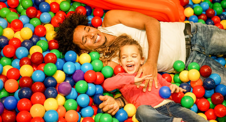 Fototapeta na wymiar Young father playing with his daughter inside ball pit swimming pool