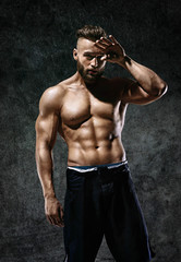 Fototapeta na wymiar Tired athletic man wiping sweat his hand. Photo of man with perfect body after training. Strength and motivation