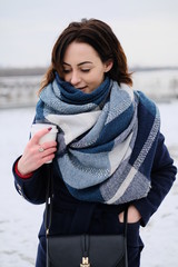 Portrait of attractive young woman wearing scarf and holding white coffee cup on a cold and snowy winter day